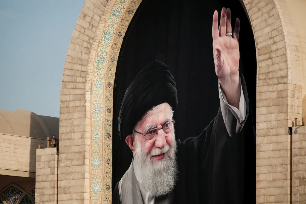 A large mural of Ali Khamenei on display above mourners.