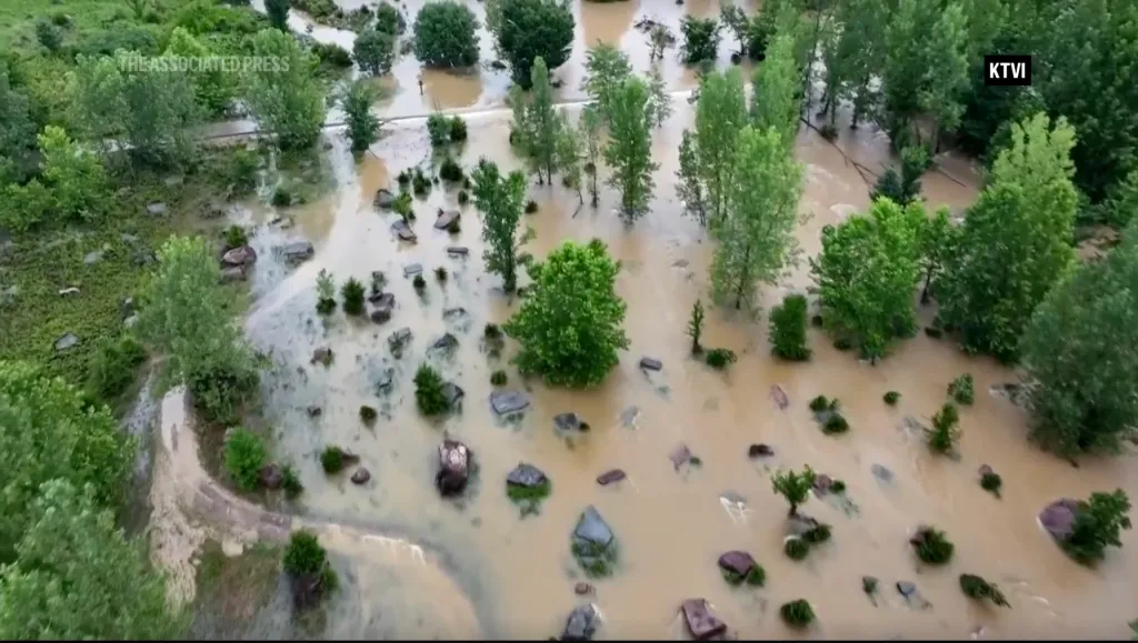 Aerial view of a flooded campground in Missouri with dirty brown water covering the ground and partially submerging trees and rocks.