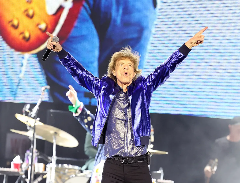 Mick Jagger of The Rolling Stones performs on stage with arms raised.