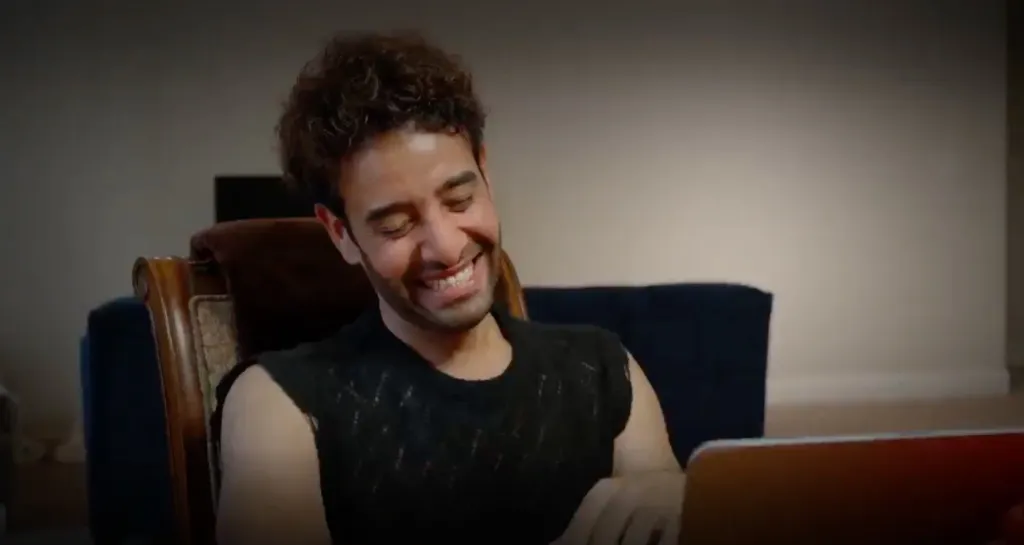Mido from 90 Day Fiancé smiling while looking at a tablet.