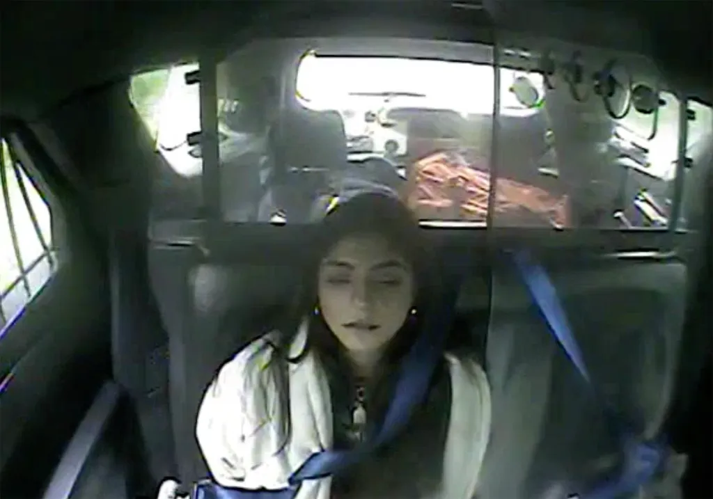 Milania Giudice sitting in the back of a vehicle with a seatbelt on, captured from a bodycam.