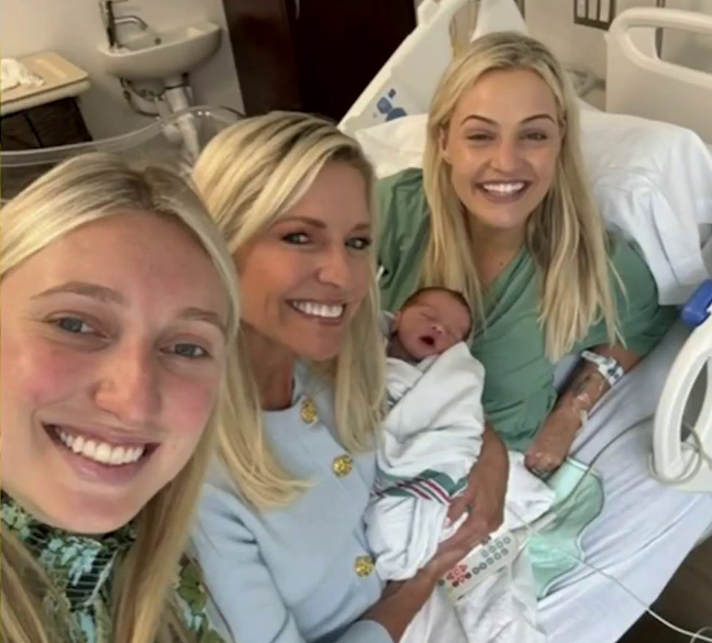 Three women and a newborn baby smiling for a photo in a hospital room.