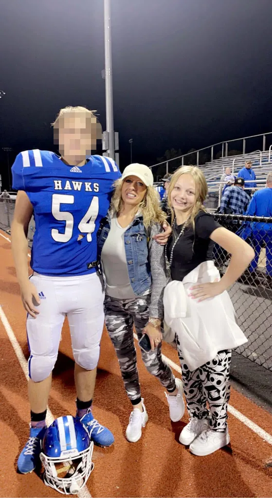 Candy Boyster (center) with her children, Gabby (right) and a male athlete, at a night football game.