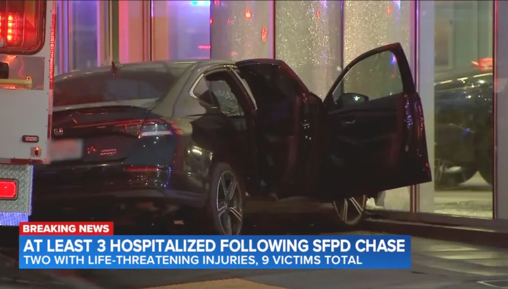 Still image of a black car with doors open next to an ambulance with a news overlay of "AT LEAST 3 HOSPITALIZED FOLLOWING SFPD CHASE TWO WITH LIFE-THREATENING INJURIES, 9 VICTIMS TOTAL".