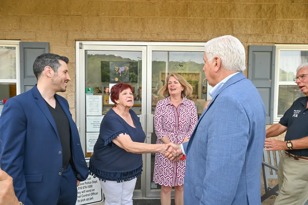 Nassau County Executive Bruce Blakeman shaking hands with a woman during an animal shelter announcement.