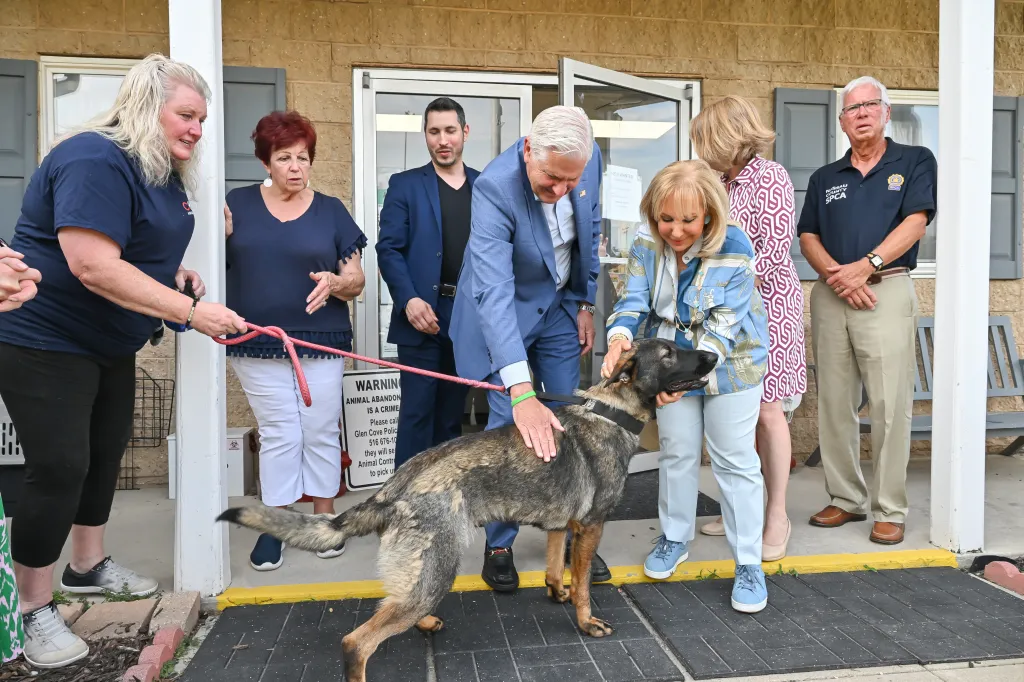 Nassau County Executive Bruce Blakeman making an animal shelter announcement while petting a dog.