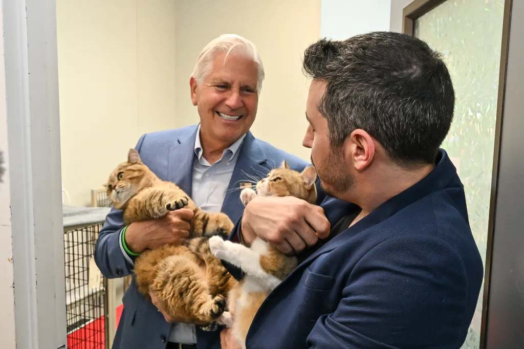 Nassau County Executive Bruce Blakeman and another man holding two tabby cats.