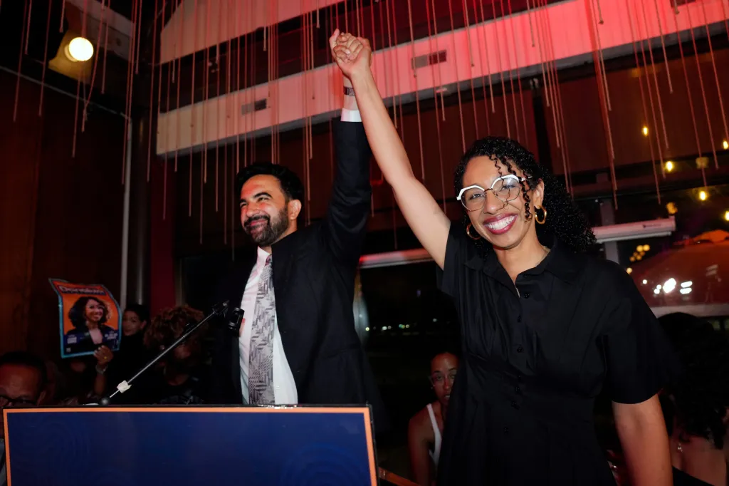 Zohran Mamdani and Darializa Avila Chevalier raise their clasped hands in celebration.