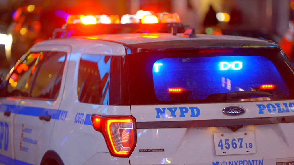 Rear view of an NYPD police car with its lights flashing.