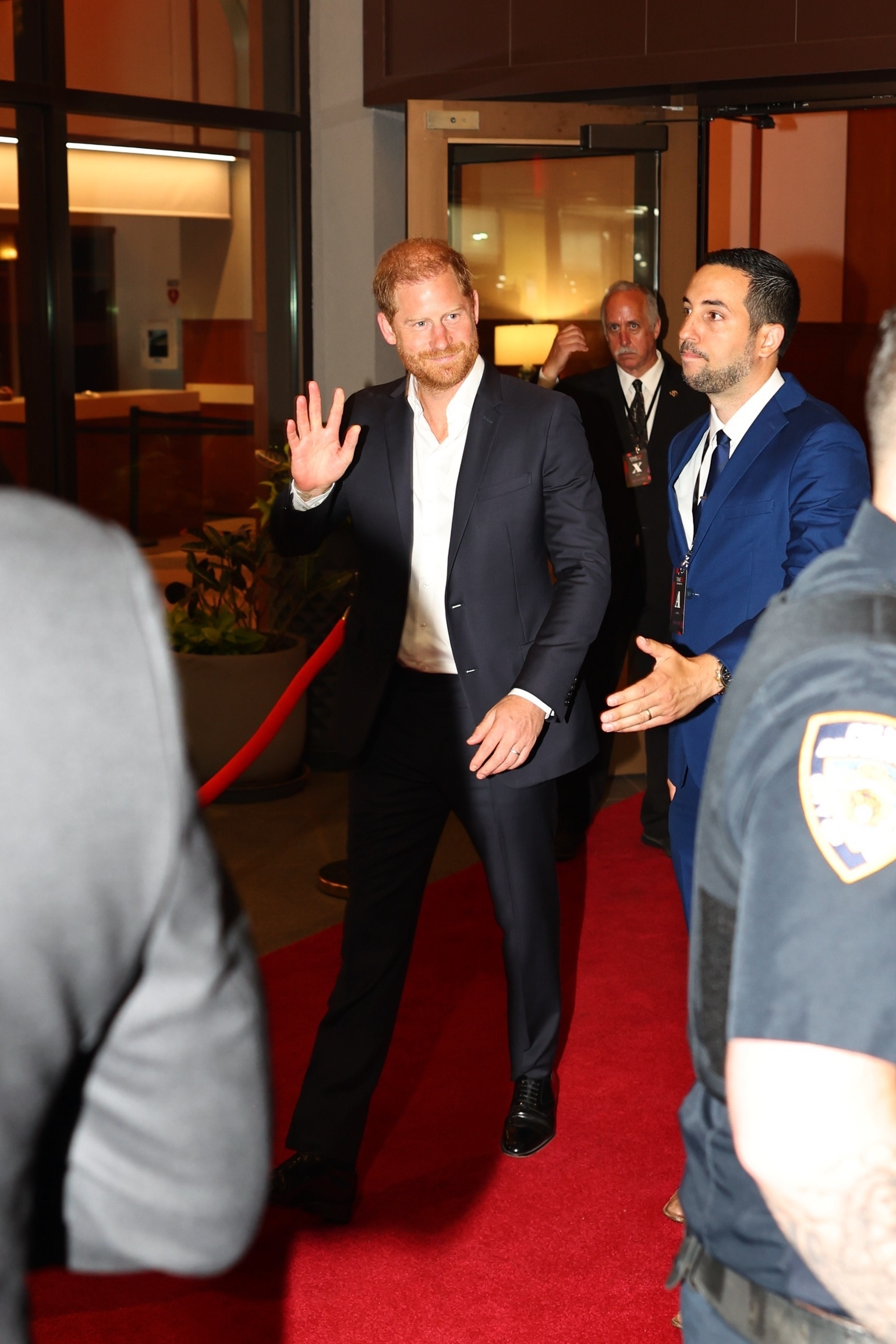 Prince Harry, Duke of Sussex, waves while exiting the Time100 Sports Gala on a red carpet.