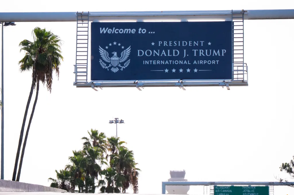 A newly installed sign reading "President Donald J. Trump International Airport" above an airport entrance.
