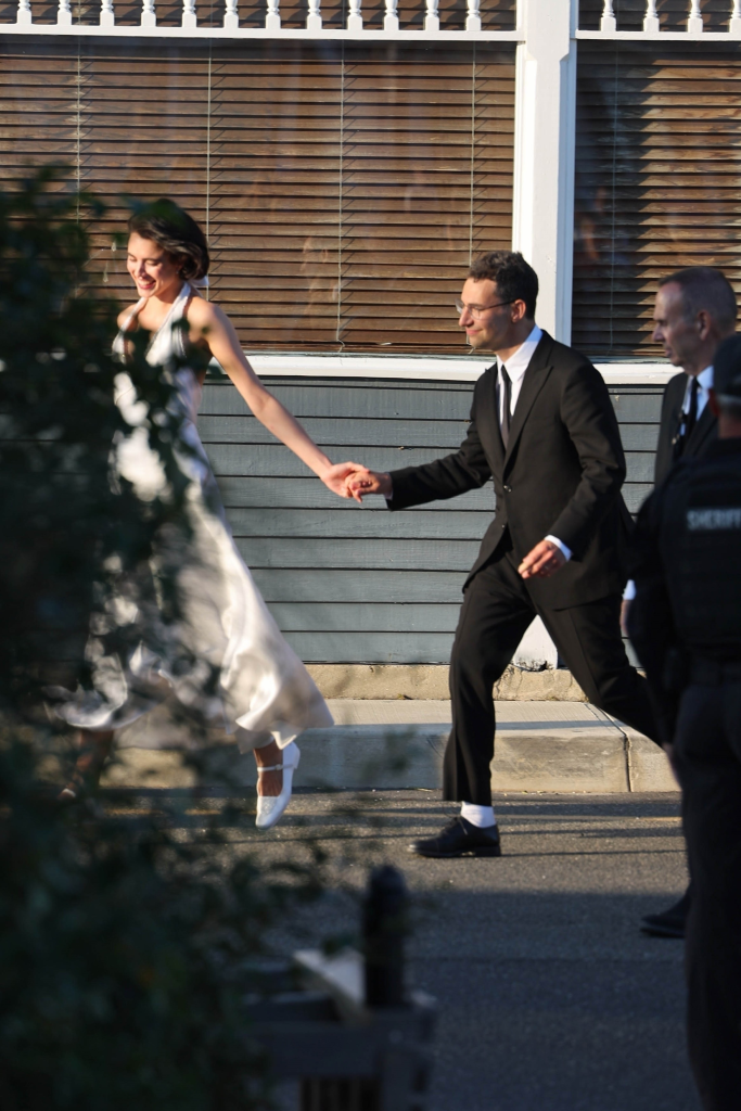 Newlyweds Margaret Qualley and Jack Antonoff smile and hold hands at their wedding reception.