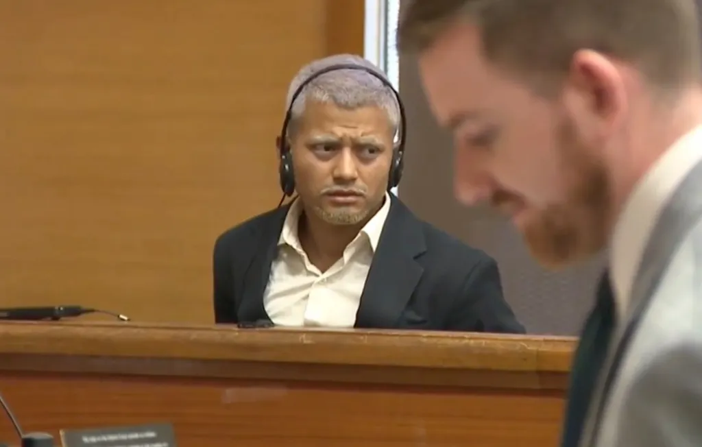 Hernan Villagran Lux in court with headphones, looking up and to the right, with another man in the foreground.