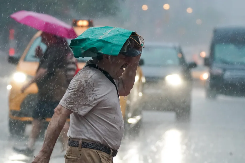A man in Hells Kitchen, NYC, uses a green bag to shield himself from a sudden heavy downpour of rain.