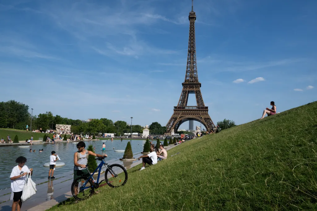 Tourists and Parisians cool off in the Trocadero fountains with the Eiffel Tower in the background during a heatwave.