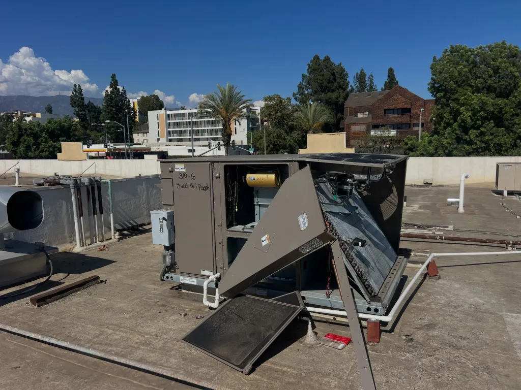 A rooftop air conditioning unit, identified as belonging to Sweet Red Peach Bakery, with an open panel revealing interior components and a missing part, indicating theft of copper wire.