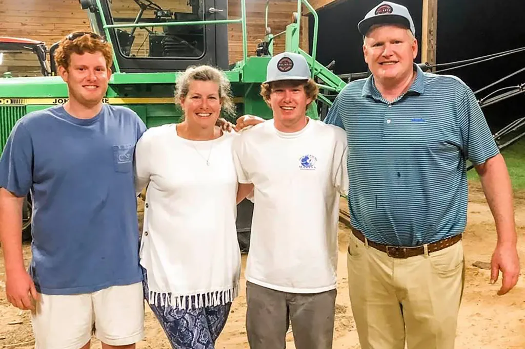 The Murdaugh family, Buster, Maggie, Paul, and Alex, smiling together in front of a tractor.