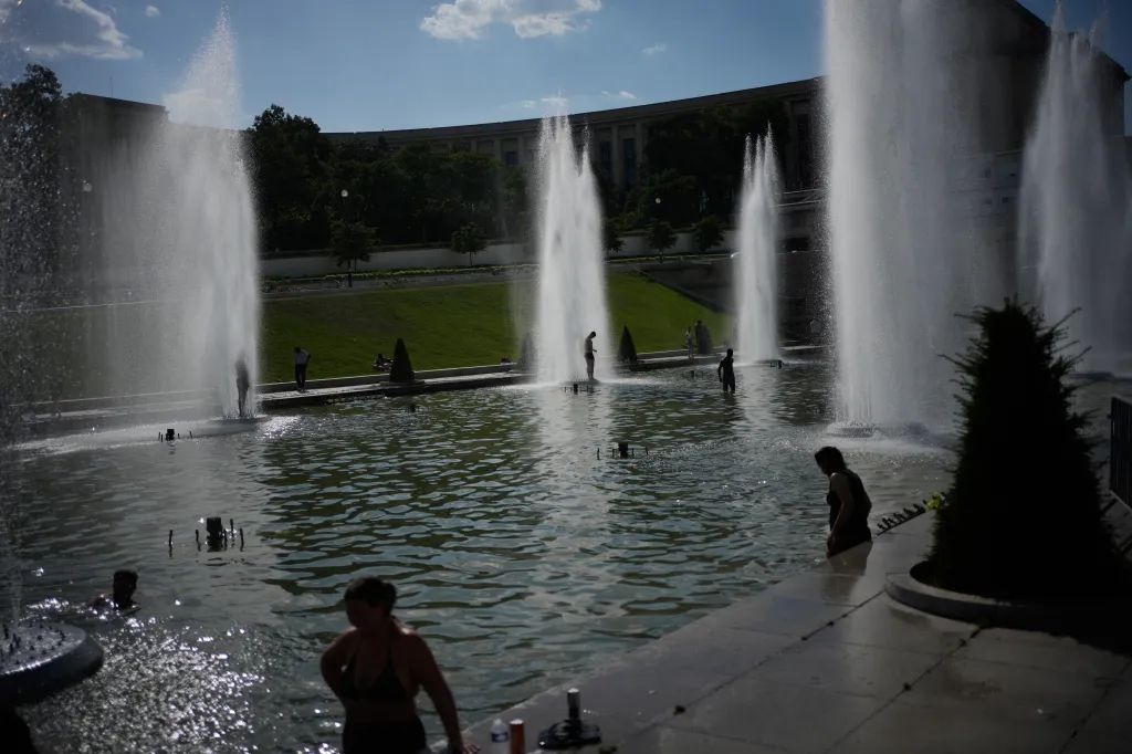 People cooling off in Trocadero fountain during a heat wave in Paris.