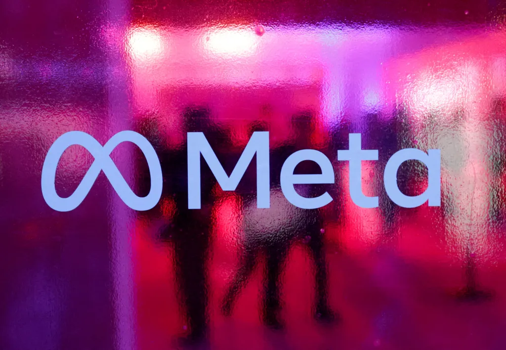 People walk behind a Meta Platforms logo at a conference.