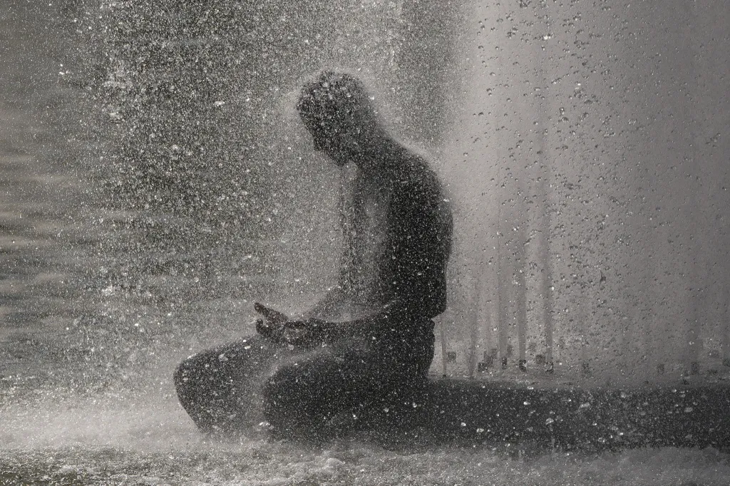 A person cools off at Trocadero fountain near the Eiffel Tower during a heat wave in Paris.