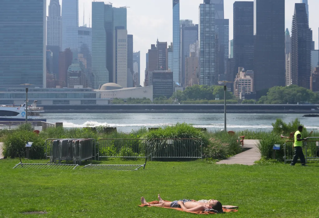 A person sunbathes in a New York City park during a heat wave.