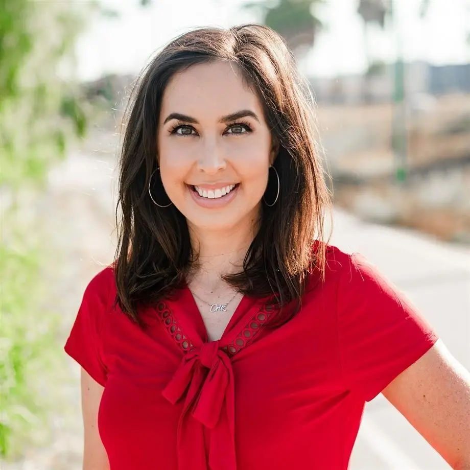 Tanya Ortiz Franklin smiling outdoors, wearing a red shirt and a necklace that reads "Ortiz".
