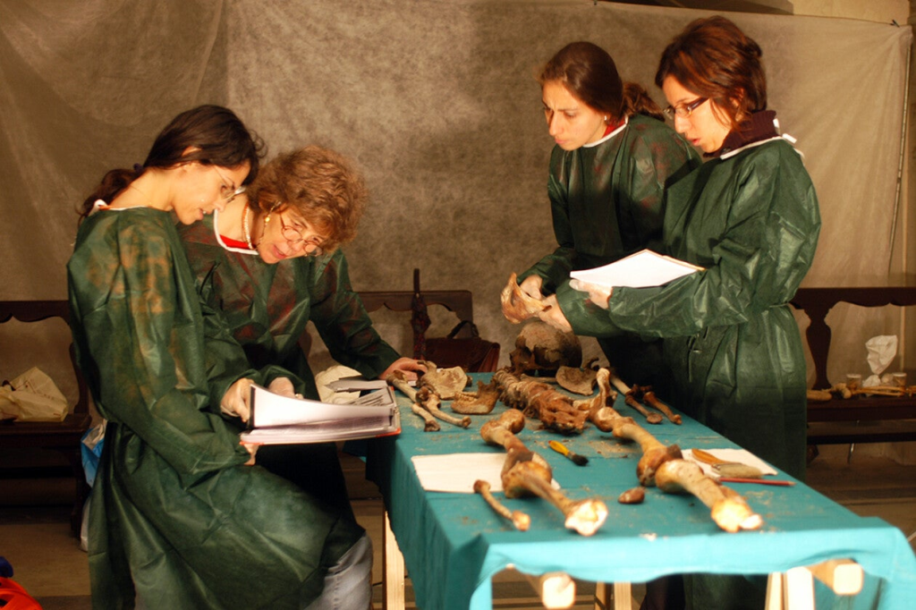 Researchers in green gowns analyzing skeletal remains of Giovanni and Francesco de' Medici for evidence of malaria.