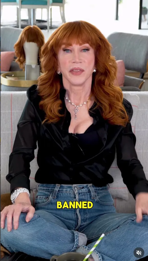 Kathy Griffin in a black top, blue jeans, and red hair.
