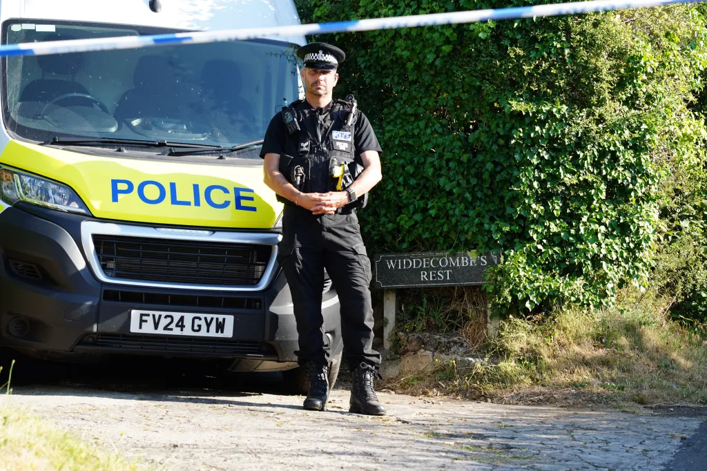 A police officer stands in front of a police van with a sign for