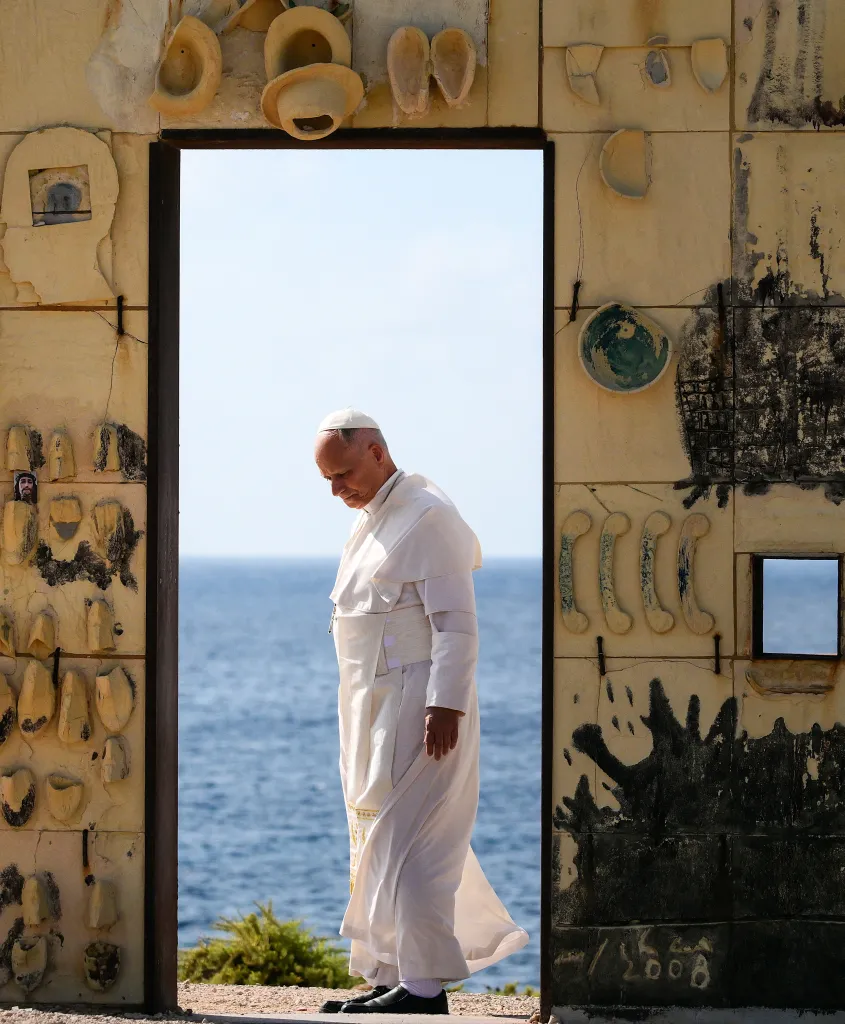 Pope Leo XIV walks through the Door of Europe monument, made by artist Mimmo Paladino, with the sea in the background.