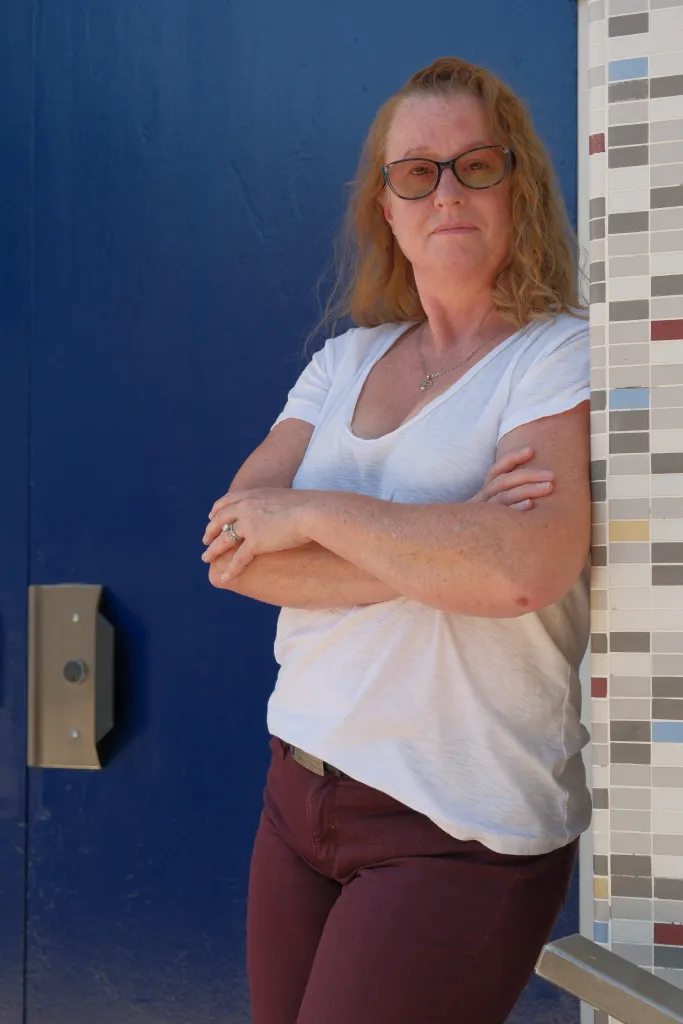 Portrait of Sonia Reiter, 48, against a blue wall with a tiled pillar to her right.