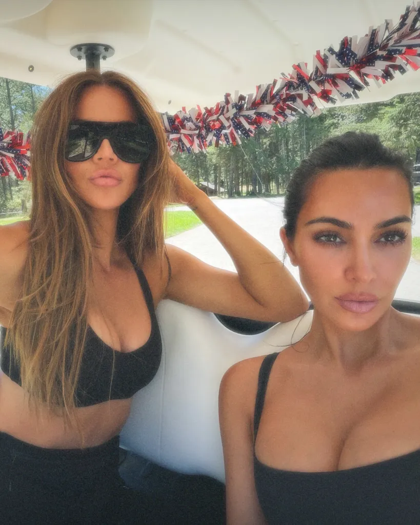 Khloe and Kim Kardashian in a golf cart decorated with red, white, and blue tinsel.