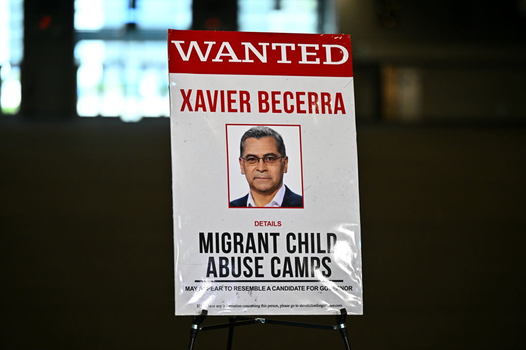 A "WANTED" poster with a photo of Xavier Becerra, linking him to "Migrant Child Abuse Camps."