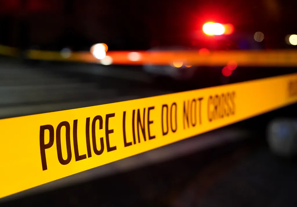 Police Line Do Not Cross tape at a crime scene at night.