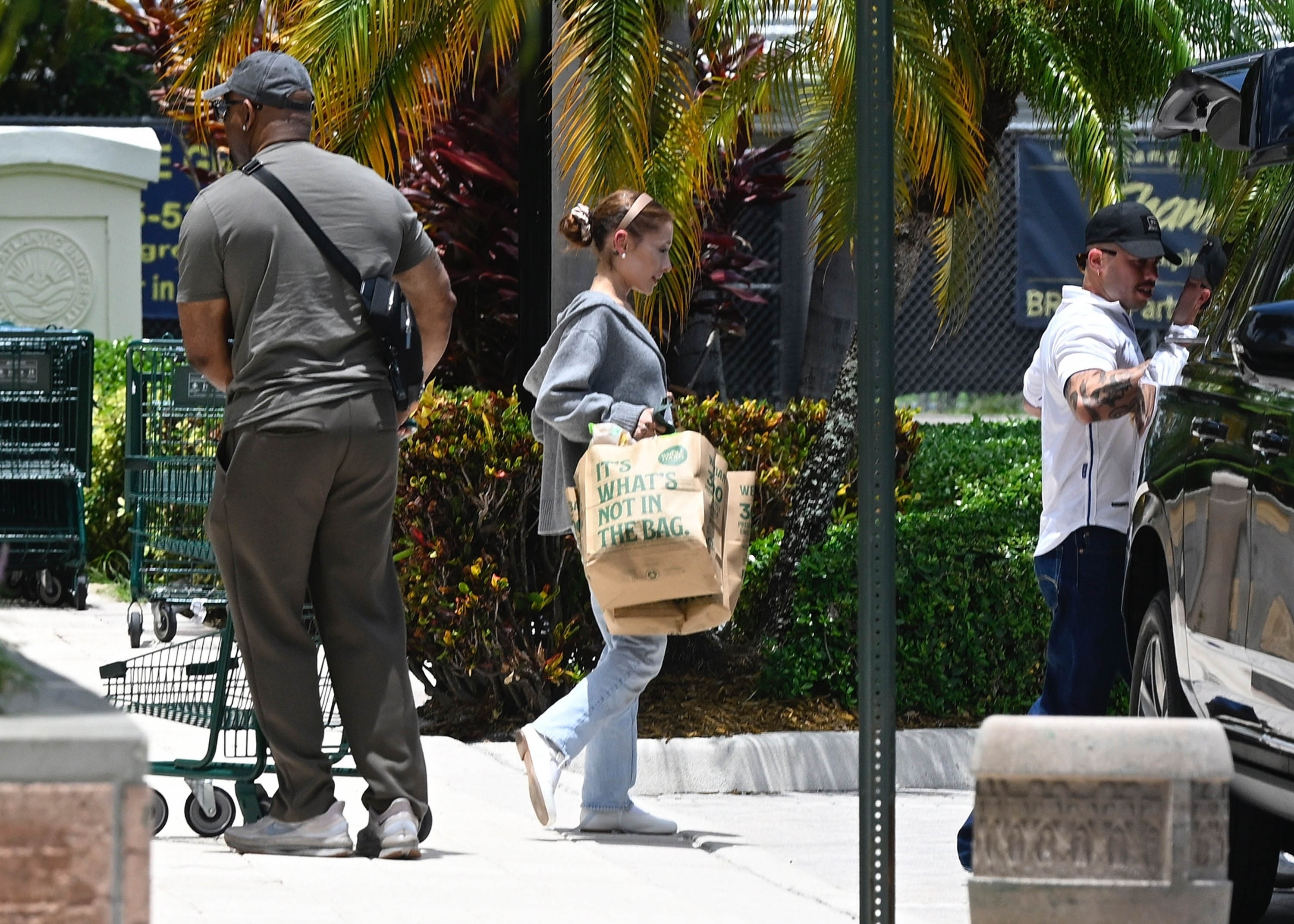 Ariana Grande carrying groceries in a brown paper bag labeled