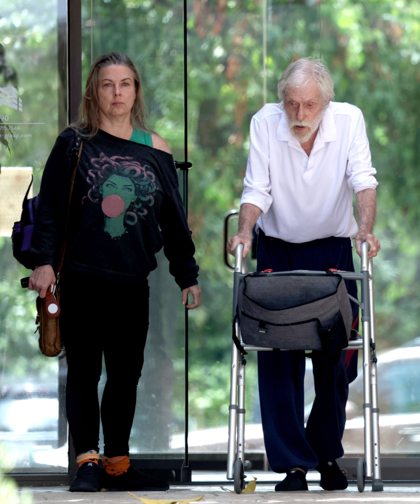 Dick Van Dyke using a walker and his wife, Arlene, standing beside him.