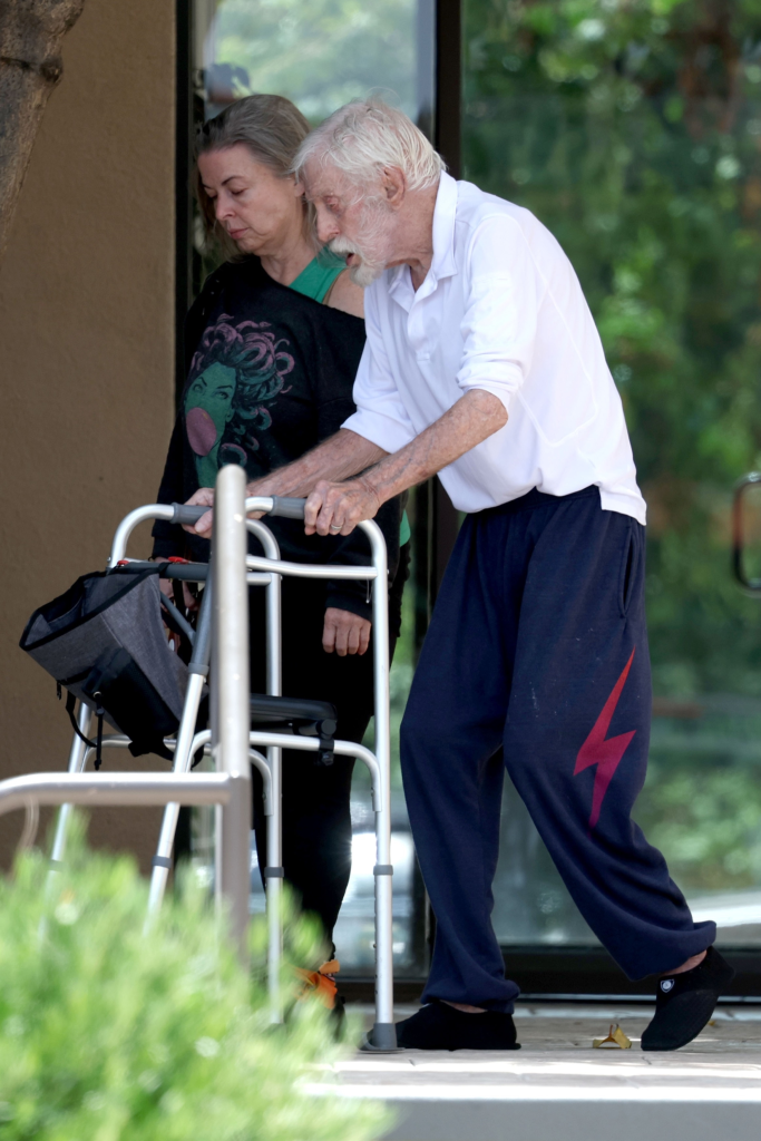 Dick Van Dyke walking with a walker alongside his wife, Arlene.