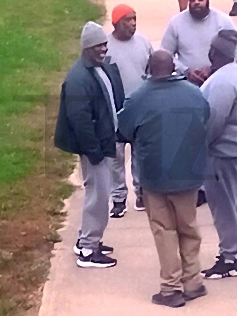Diddy smiling and chatting with inmates in a prison yard.