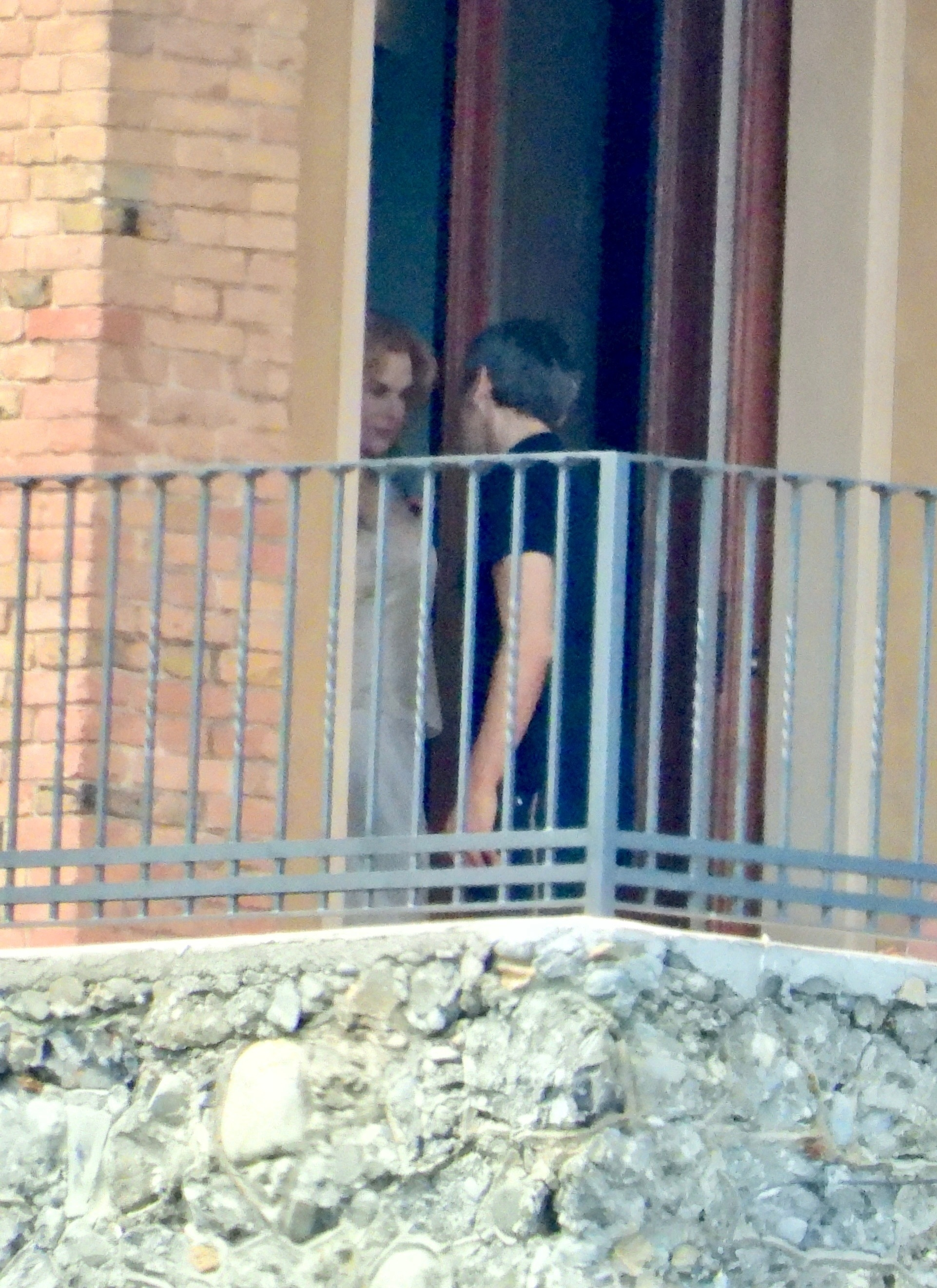 Nicole Kidman and a man sharing a farewell on a balcony.