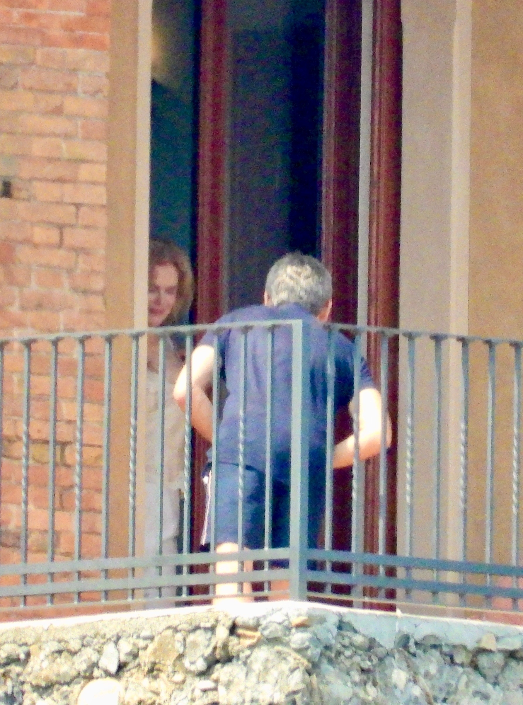 Nicole Kidman and a mystery man behind a balcony railing.