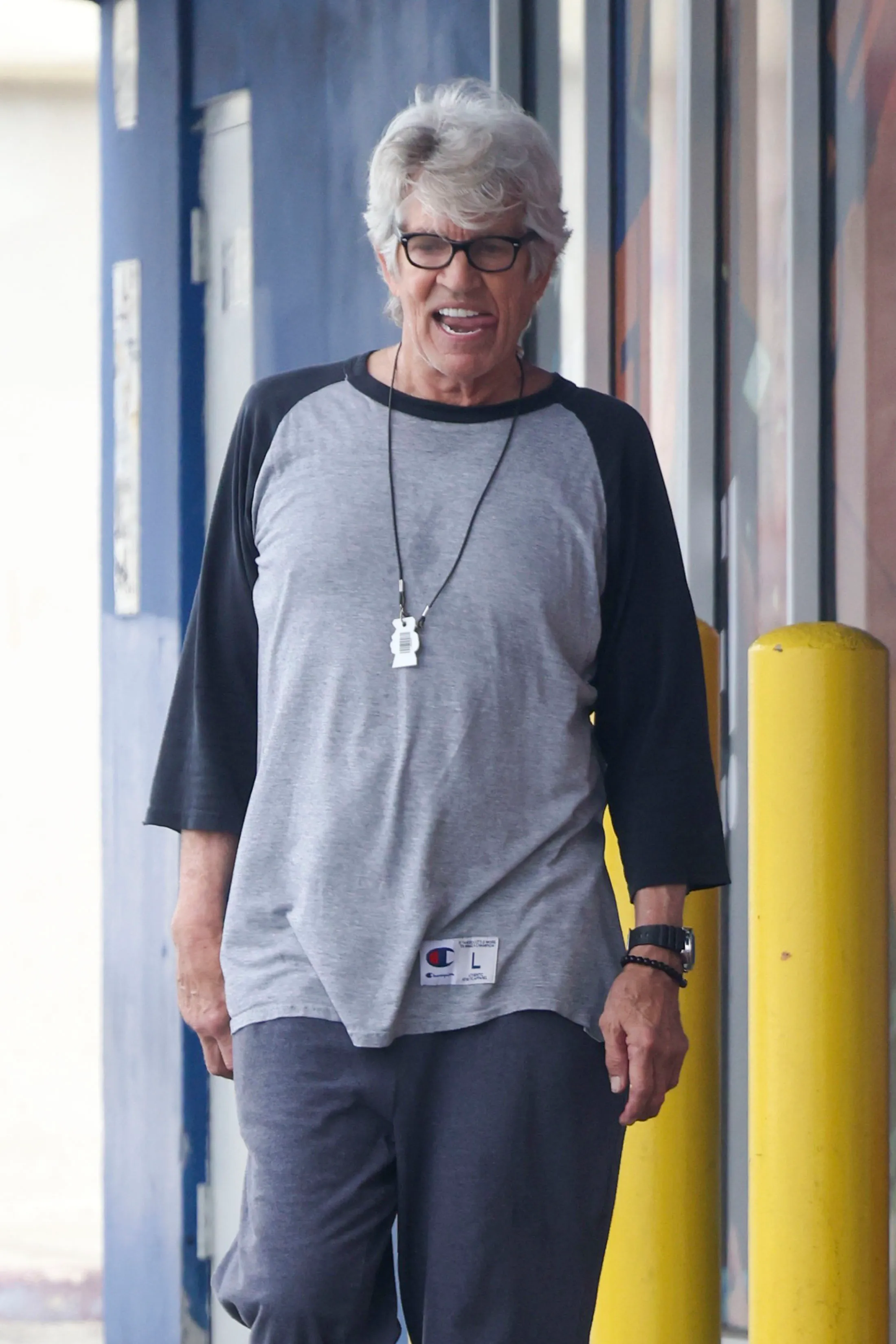 Eric Roberts leaves Crunch Gym wearing a gray and black raglan shirt and black sweatpants.