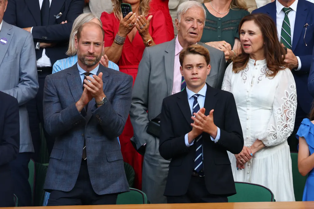 Prince William and Prince George of Wales clapping in the stands at Wimbledon.
