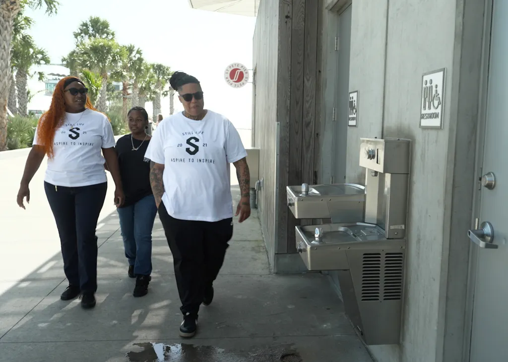 Rashan Williams, 41, walking with two other individuals while wearing an "Aspire to Inspire" shirt.