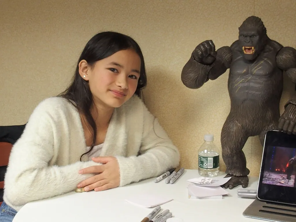 Kaylee Hottle sitting next to a Kong action figure at a conference.