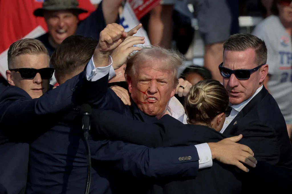 Donald Trump being assisted by the Secret Service after gunfire at a rally.