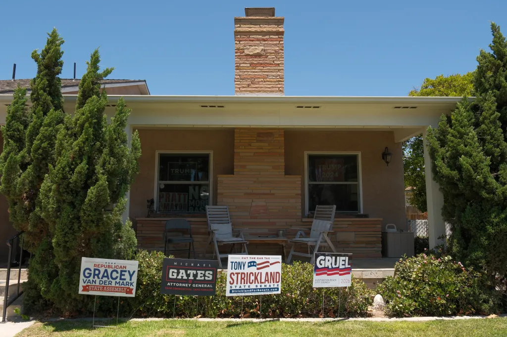 A house in Huntington Beach, California, with multiple political campaign signs in the yard and “Trump 2024” signs in the windows.