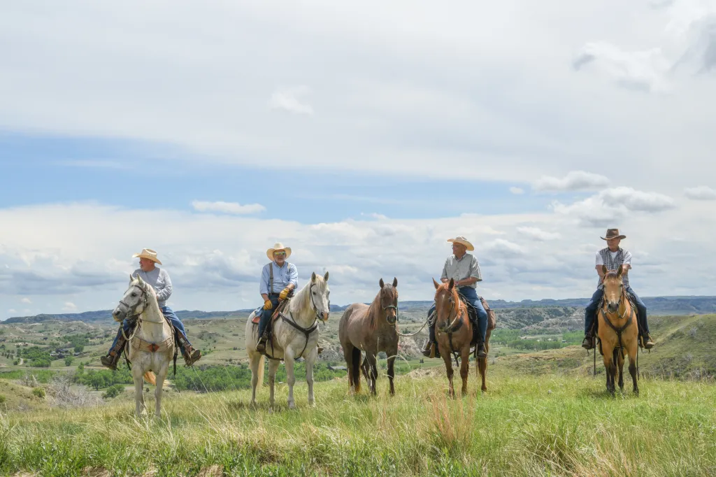 Four riders on horseback in Medora, North Dakota, with hills and plains in the background.