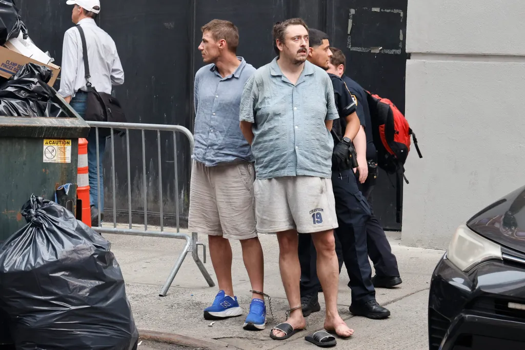Two men in handcuffs standing with police officers.