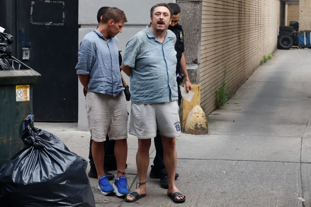 Police escorting Andrew Truelove and another man, both in handcuffs, after Truelove was arrested for shouting racist slurs at a TV co-host.