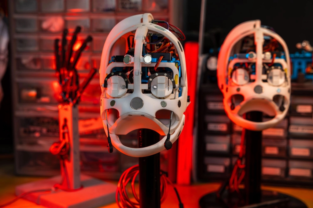 Close-up of a robot's internal components, with another robot head in the background.